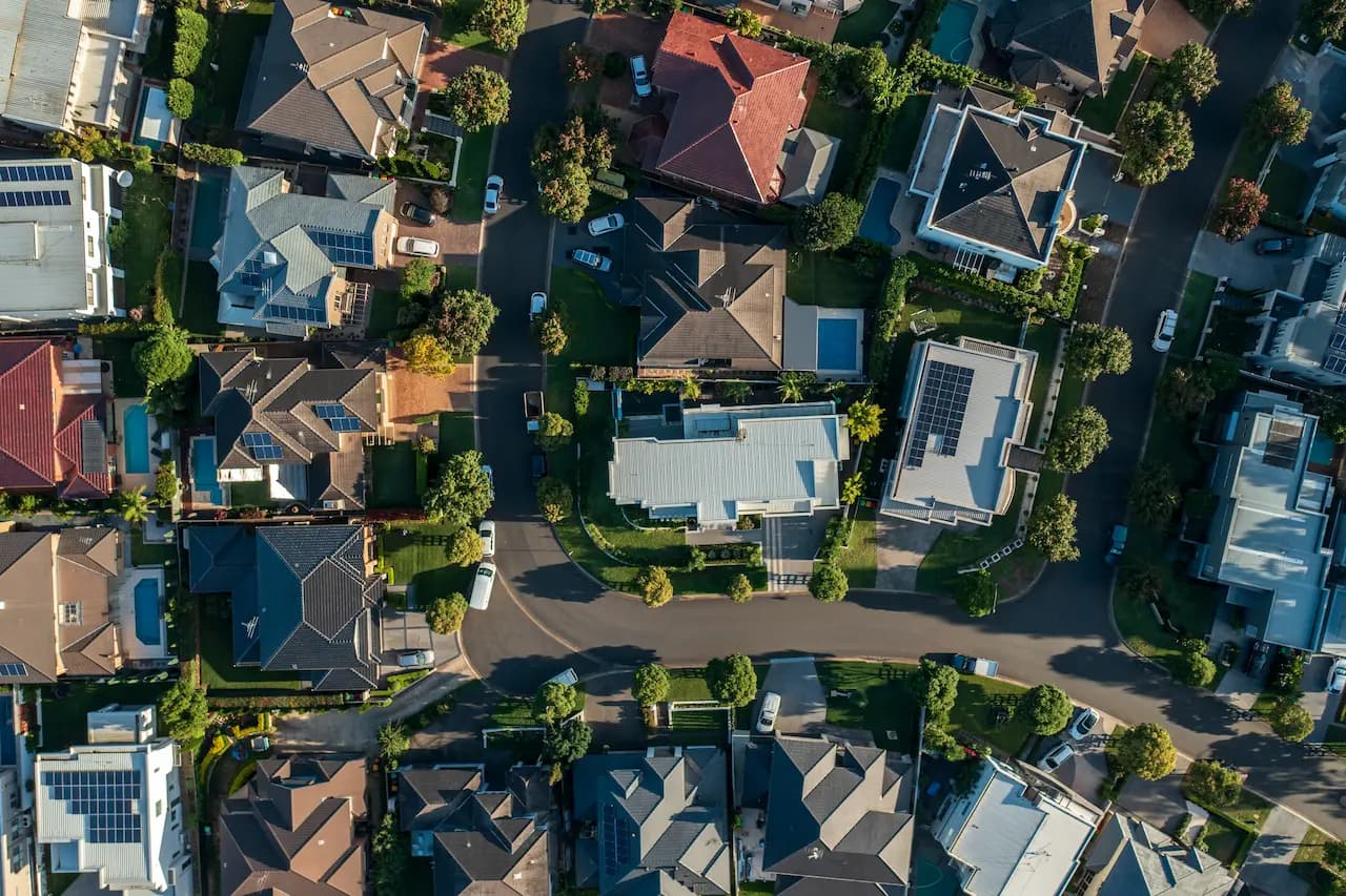 Aerial view of Australian suburban houses with rooftops, solar panels, and tree-lined streets